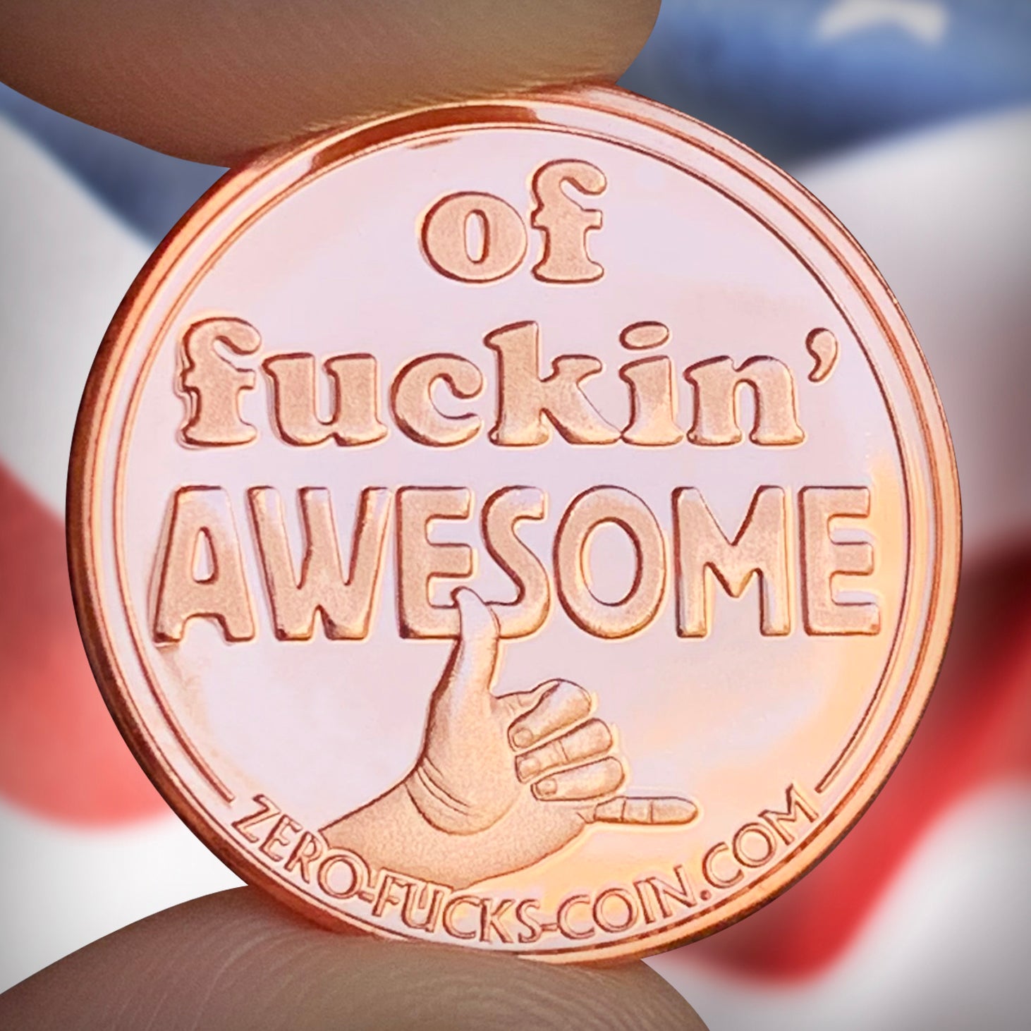 copper coin with 'of fuckin' AWESOME' text and a hand giving a thumbs up shaka, held by a hand against a blurred background.