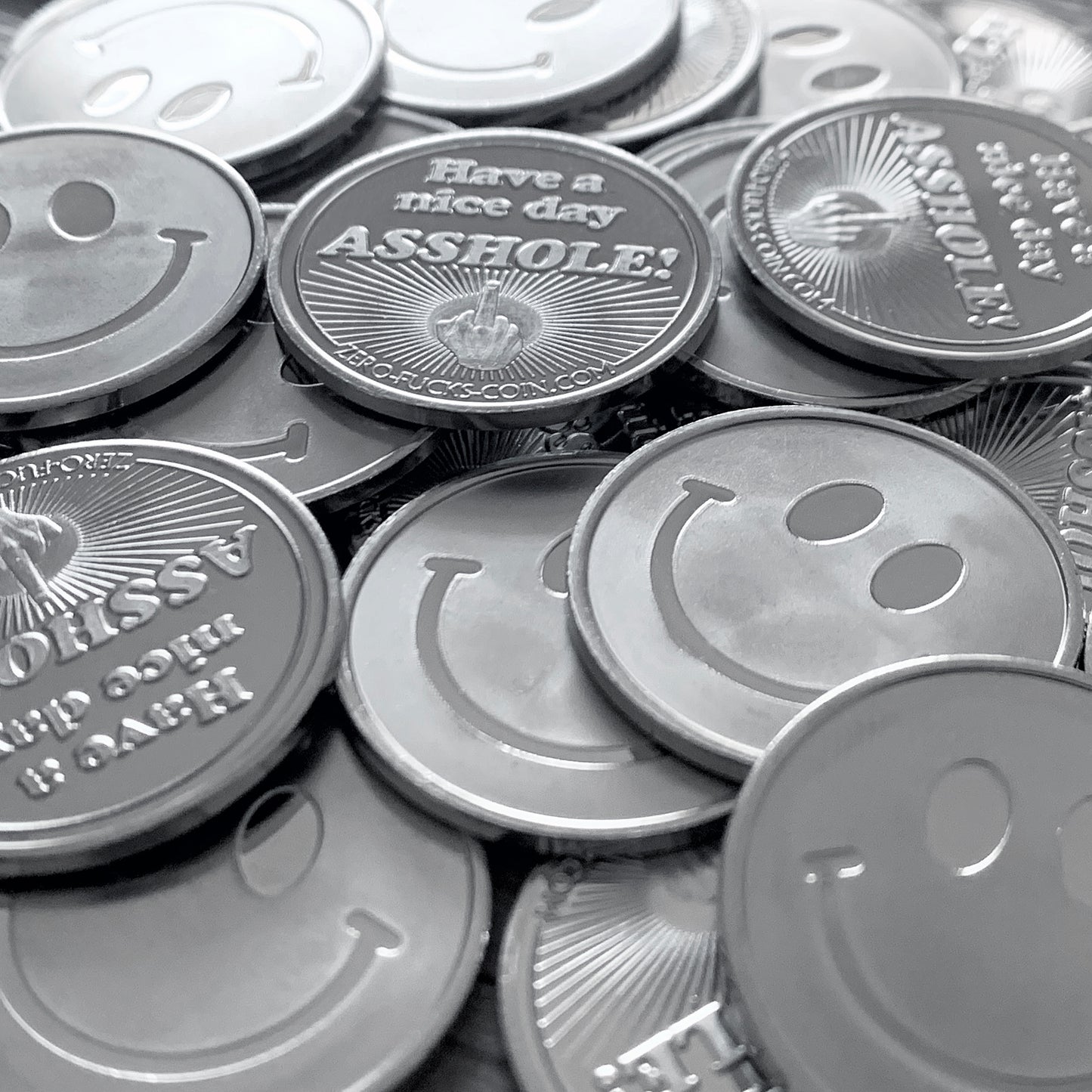 Stack of coins with smiley faces and one with a offensive message