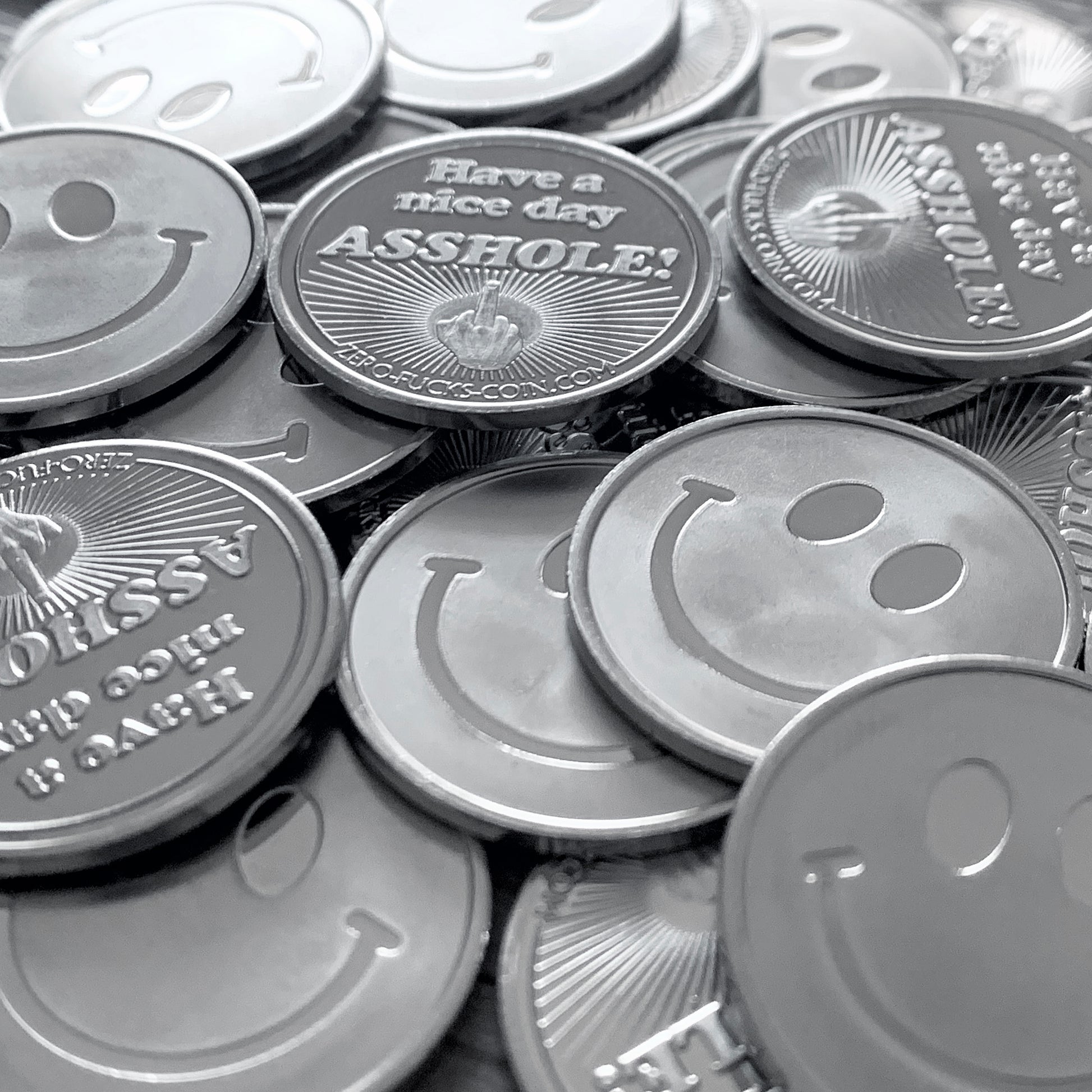 Stack of coins with smiley faces and one with a offensive message