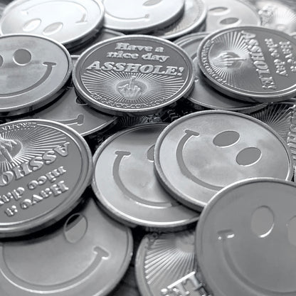 Stack of coins with smiley faces and one with a offensive message