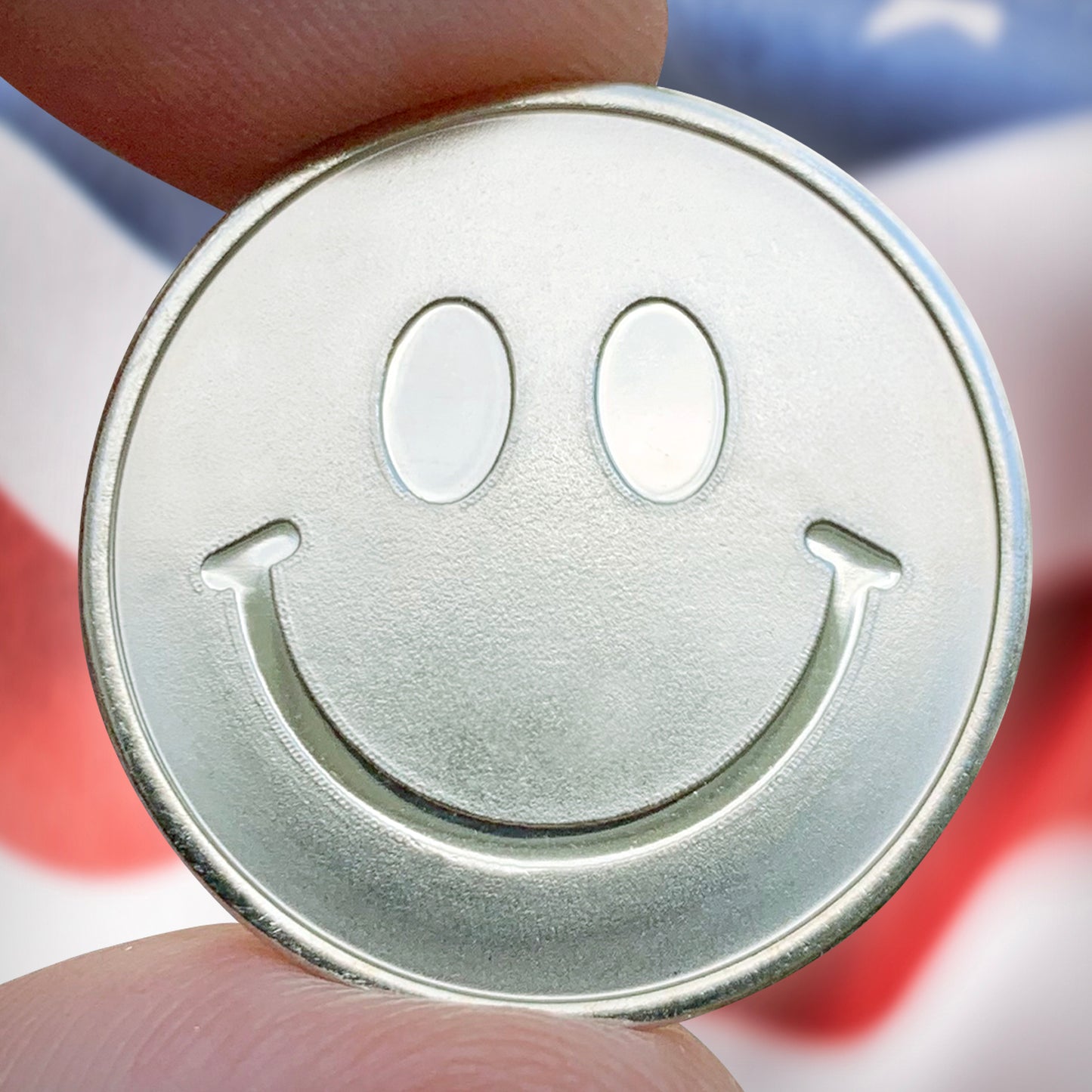Metallic smiley face coin held between fingers 